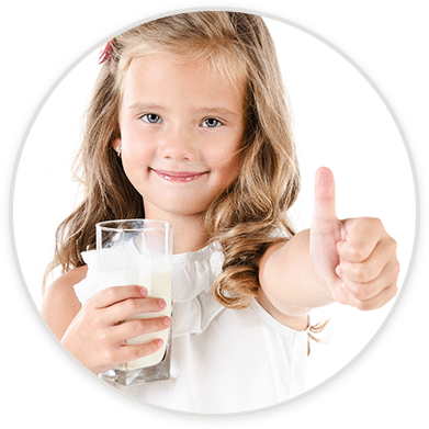 Smiling girl holding a glass of milk with a thumbs-up gesture.